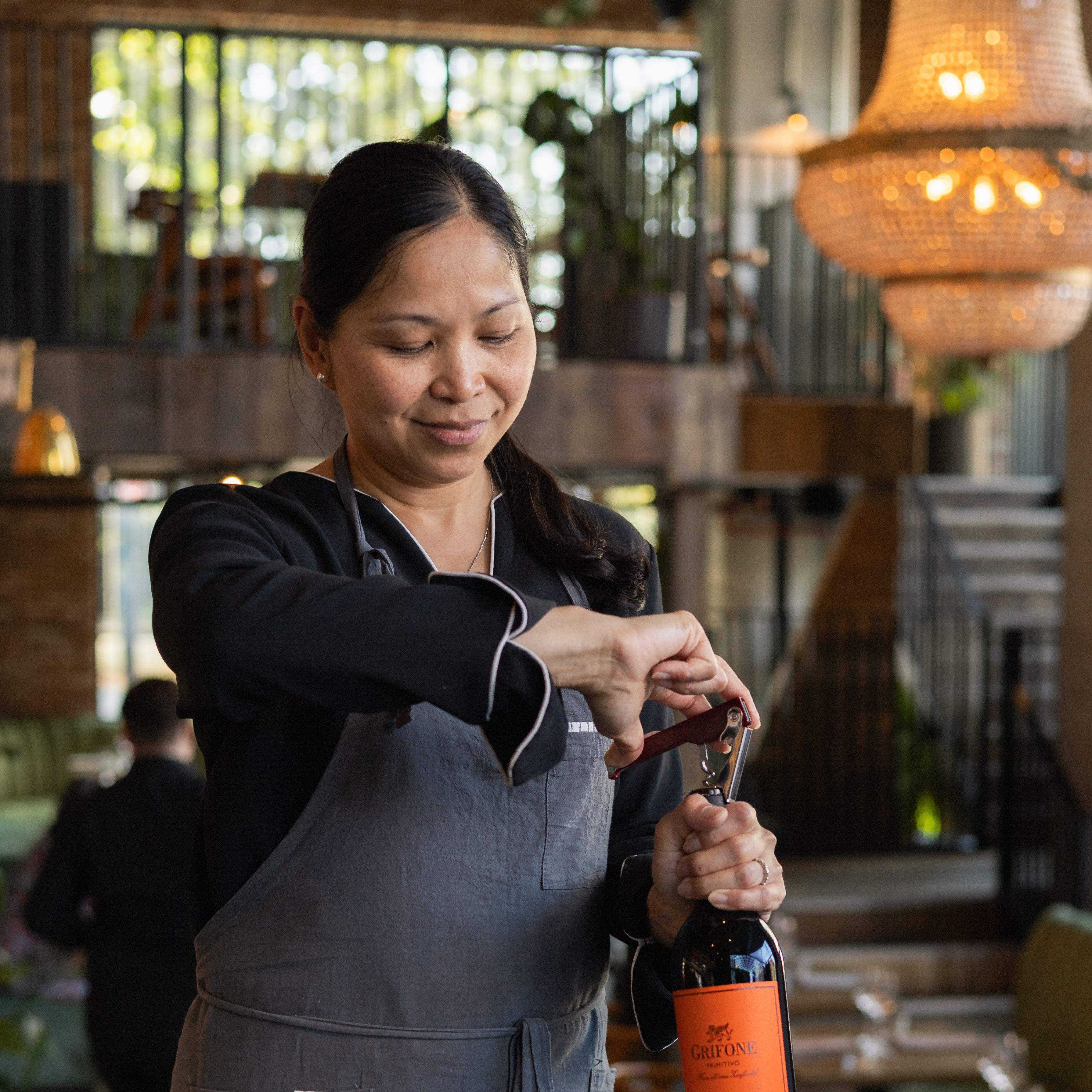 A waiter opening a bottle of wine