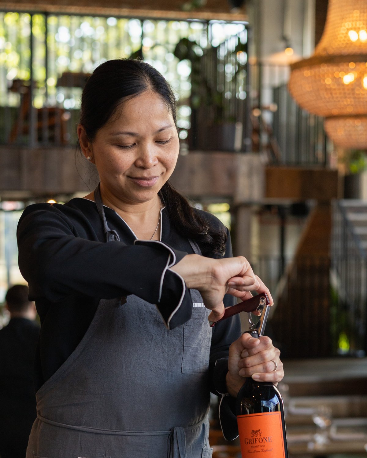 A waiter opening a bottle of wine