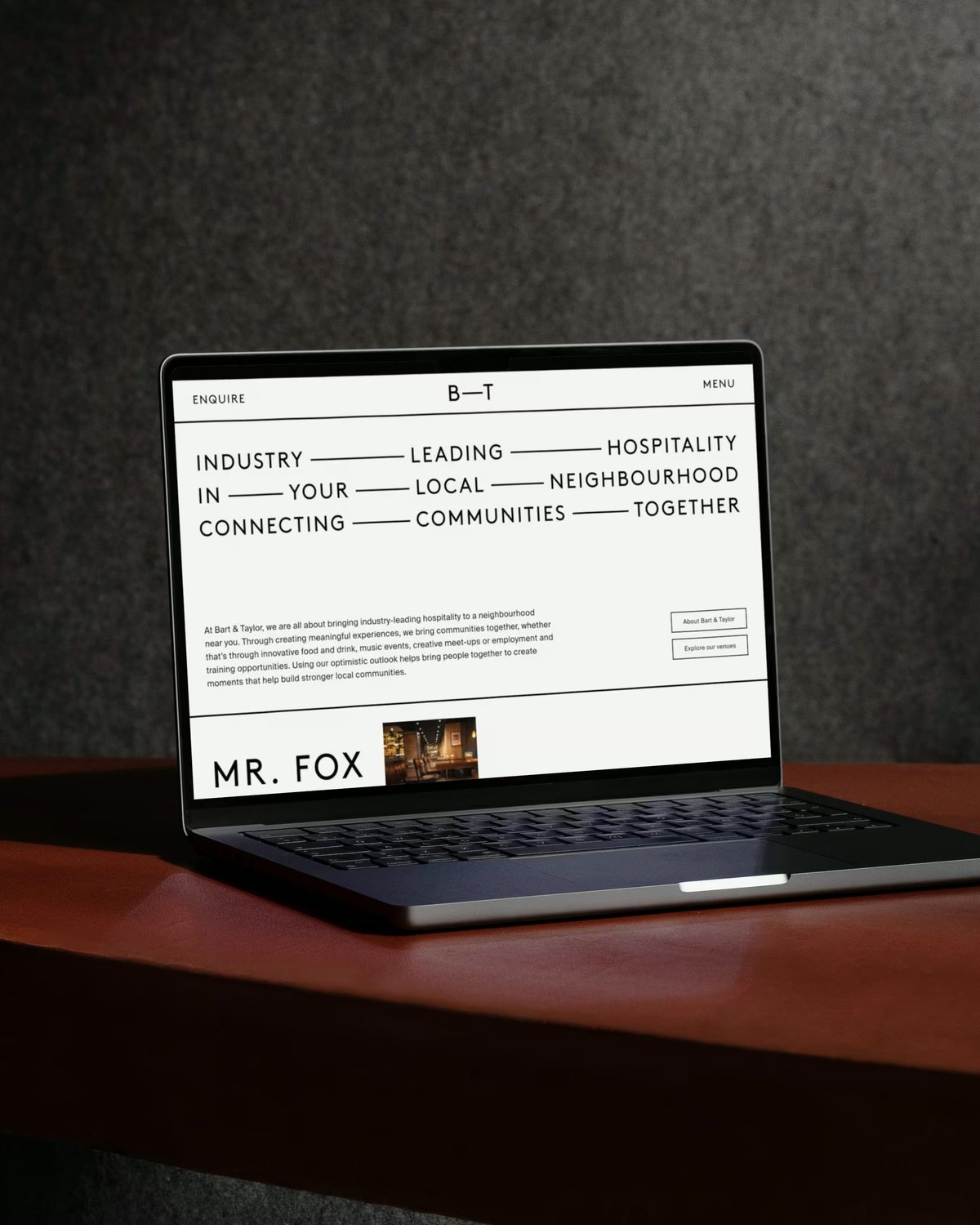 A laptop open on a dark wooden table, displaying a website mockup for Bart & Taylor (B—T) with bold typography reading "Industry Leading Hospitality in Your Local Neighbourhood Connecting Communities Together."