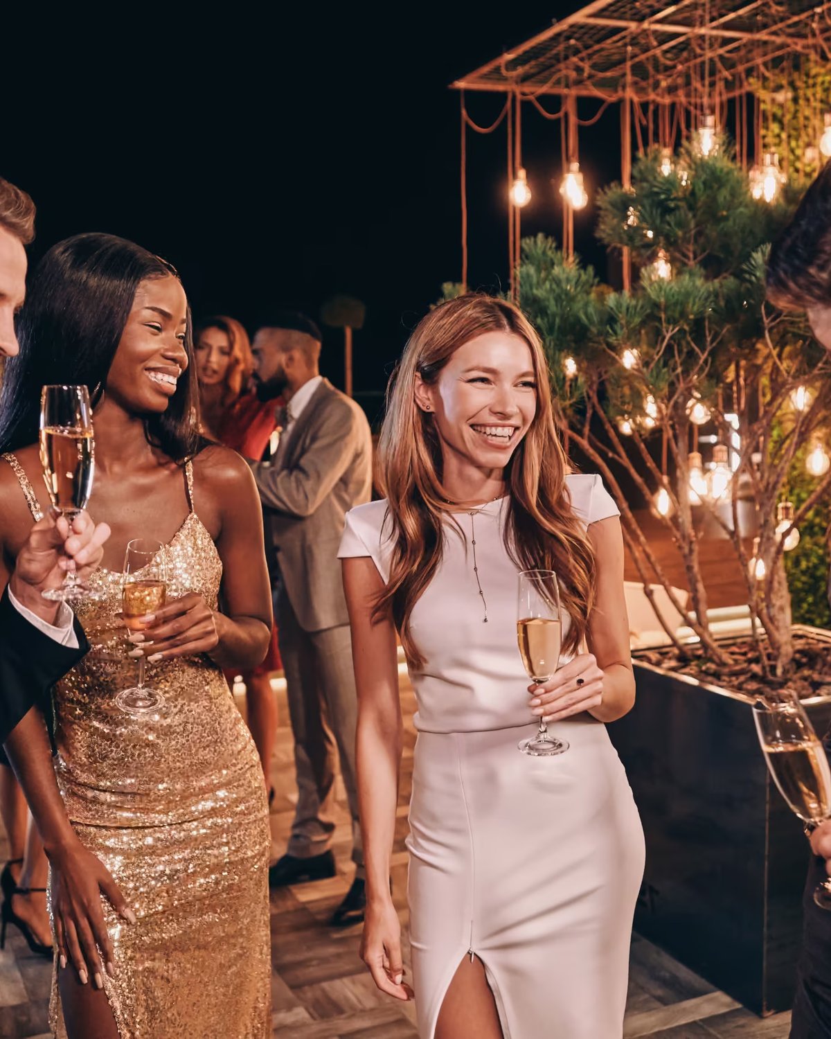 A group of well-dressed people enjoying champagne at an upscale evening venue event.