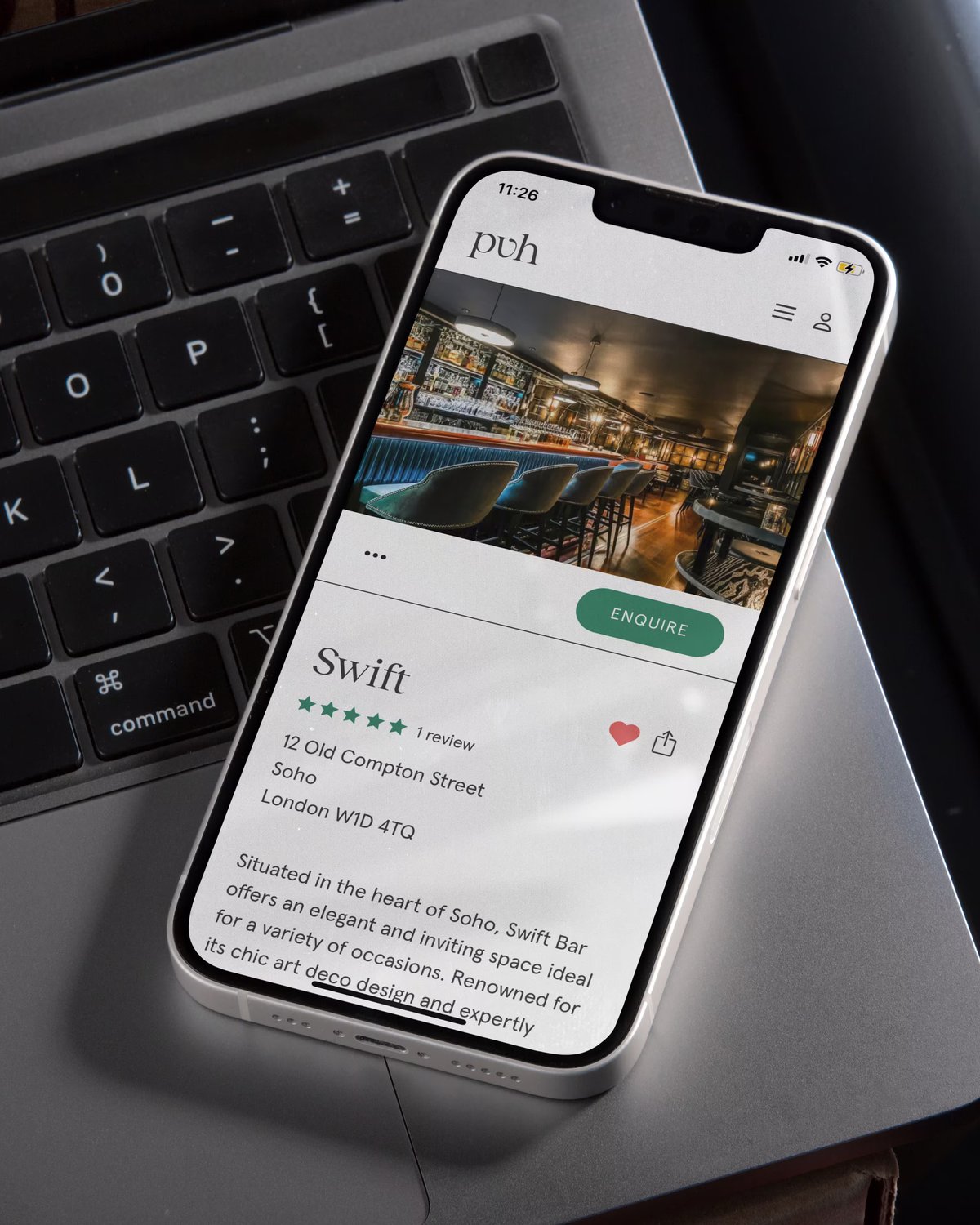 A smartphone resting on a MacBook keyboard displaying the Private Venue Hire web app venue page for Swift bar in Soho.