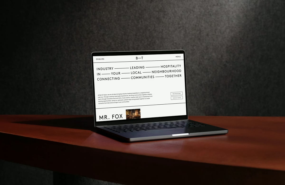 Laptop displaying the Bart & Taylor website featuring bold editorial typography reading 'Industry Leading Hospitality', minimal navigation, and a venue preview for Mr. Fox.
