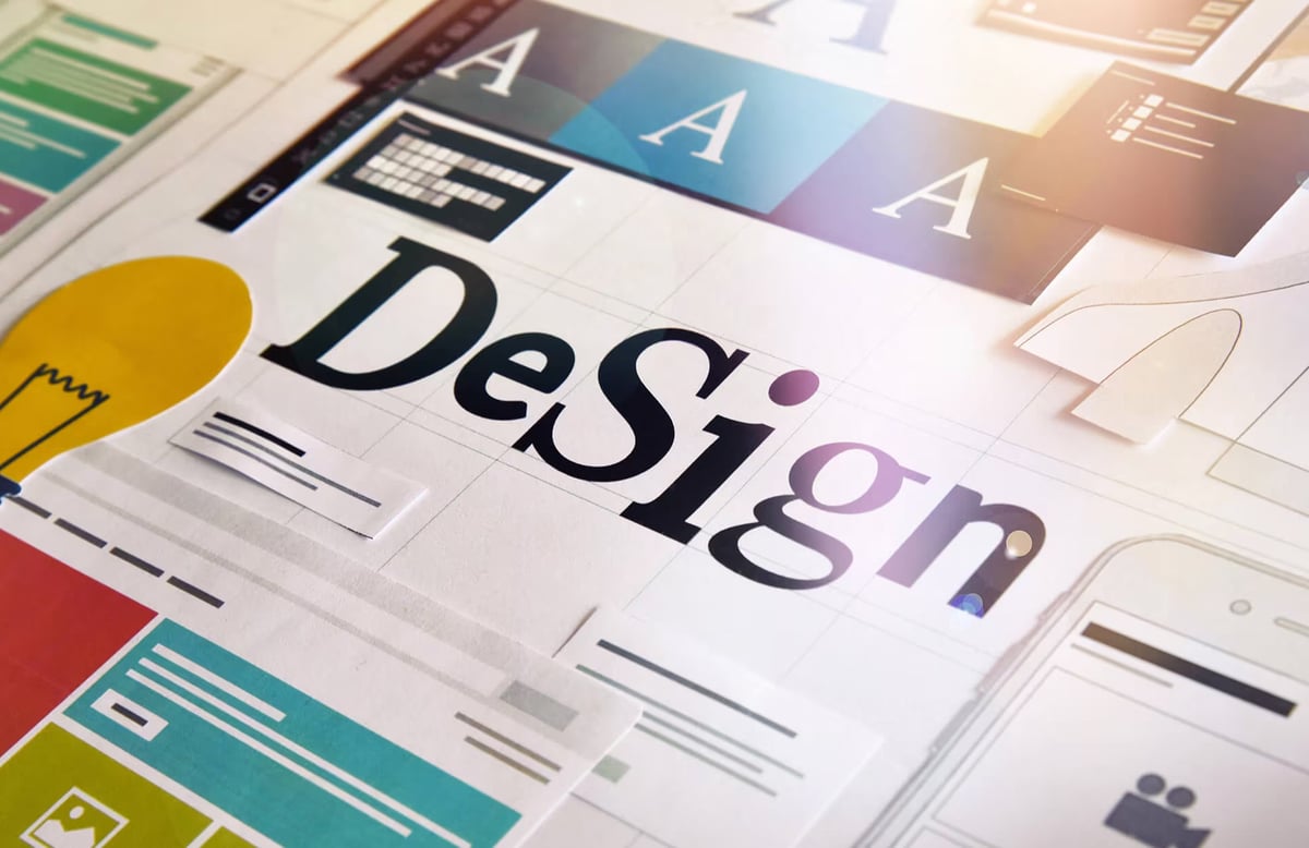 Overhead view of a web design mood board featuring a lightbulb icon, typography cards, color blocks, website layout cutouts, and a mobile screen sketch with the word Design printed in large text.