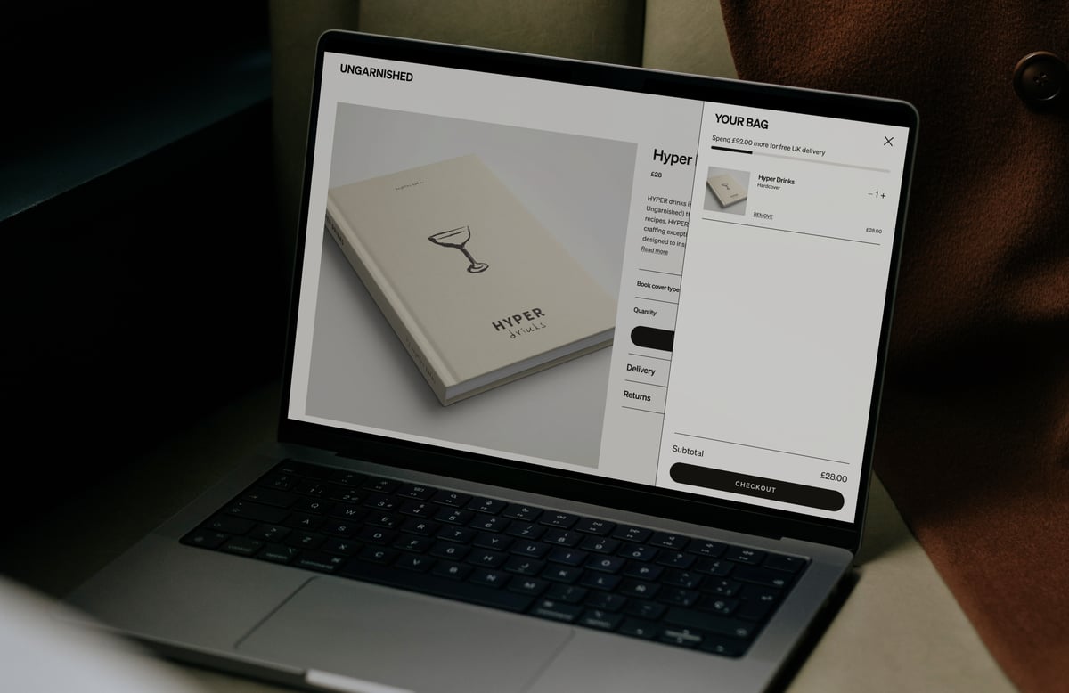 Laptop displaying the Ungarnished website with an open slide-out shopping cart drawer featuring a free delivery progress bar, item controls, and a checkout button.